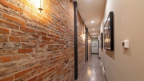 A hallway with exposed brick walls, recessed lighting, and framed pictures on the walls. - The Aerie- On Central- LeMars (LeMars)