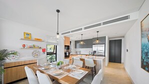 Una cucina moderna con isola centrale, sedie bianche e illuminazione a sospensione.