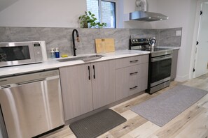 A modern kitchen with a dishwasher, microwave, stove, and sink.