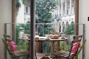 A balcony with a table set for breakfast, including croissants, a cup, and an open book. - Florence Art Apartments (Florence)