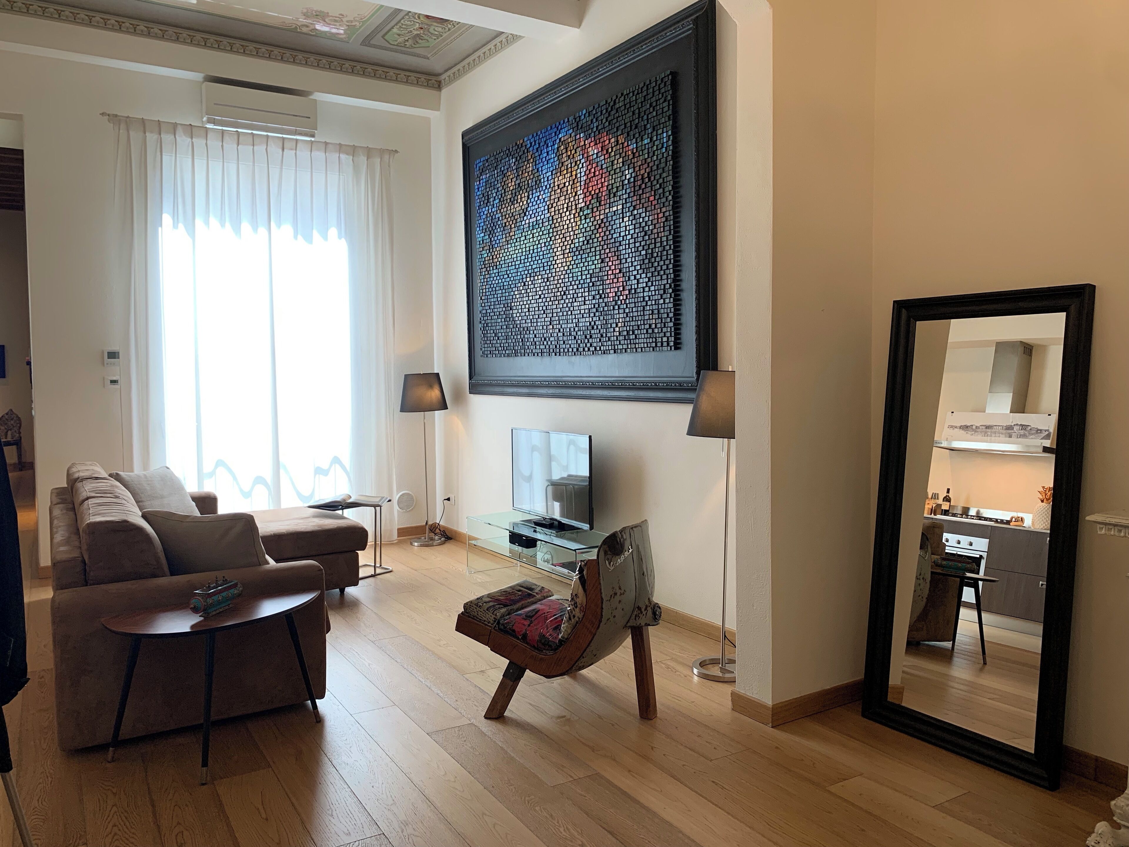 A modern living room with a sofa, a coffee table, a TV, and a large abstract painting.
