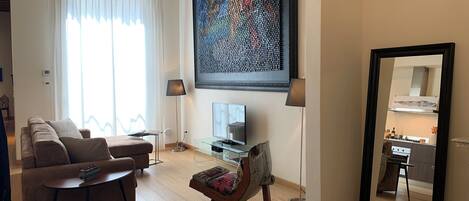 A modern living room with a sofa, a coffee table, a TV, and a large abstract painting.