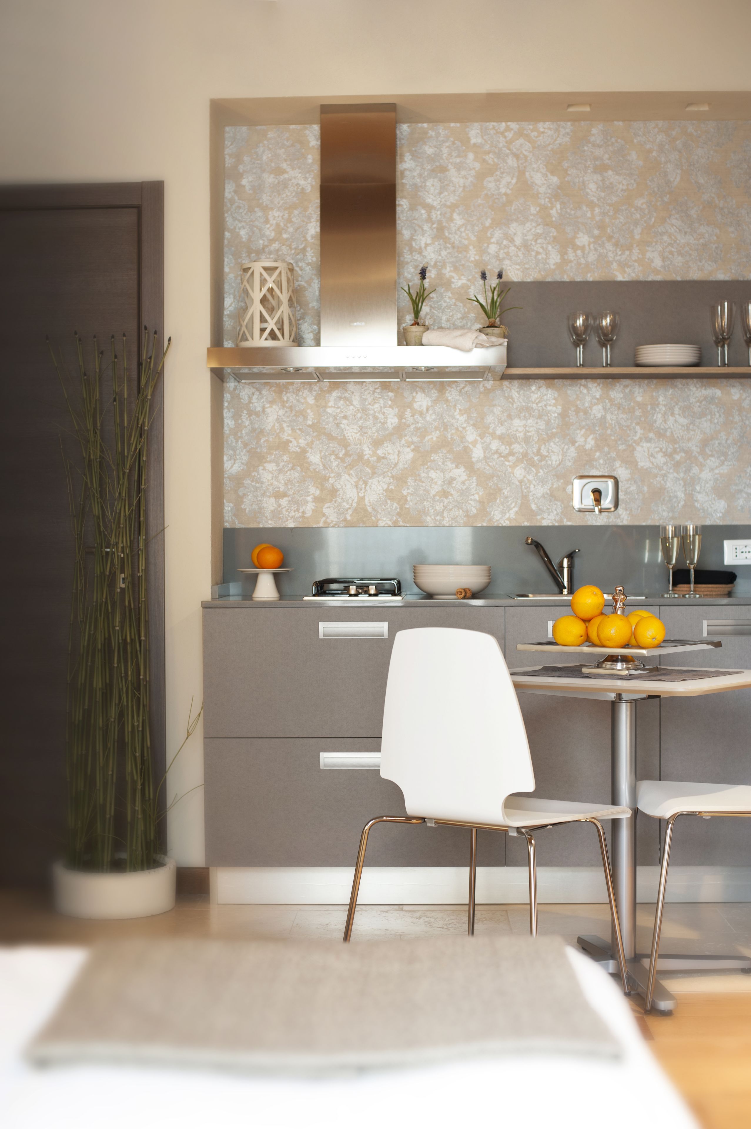 A modern kitchen with a central island, white chairs, and a potted plant.