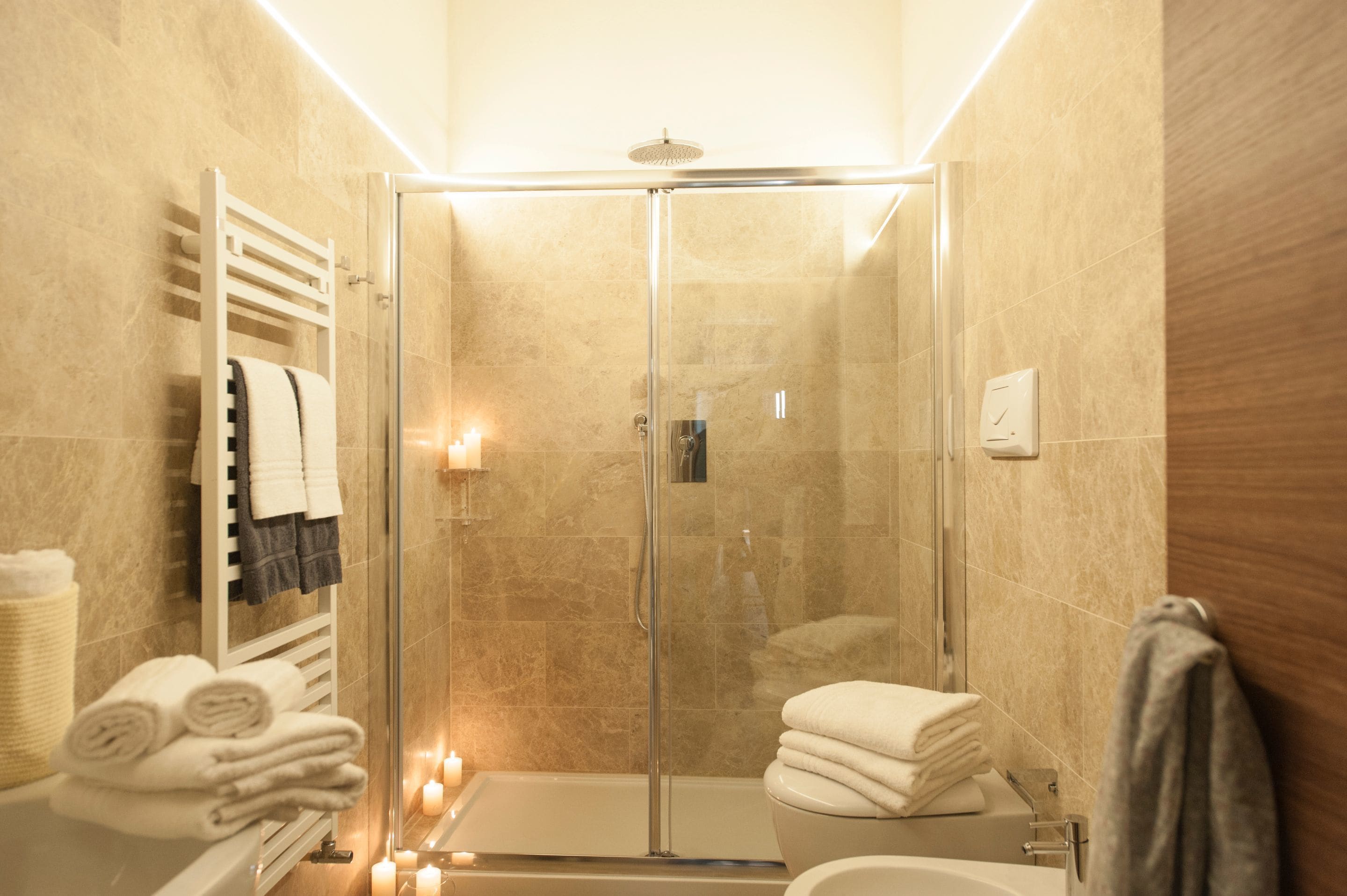 A modern bathroom with a glass-enclosed shower, a white bathtub, and a toilet.