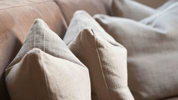 A beige sofa with multiple cushions.
