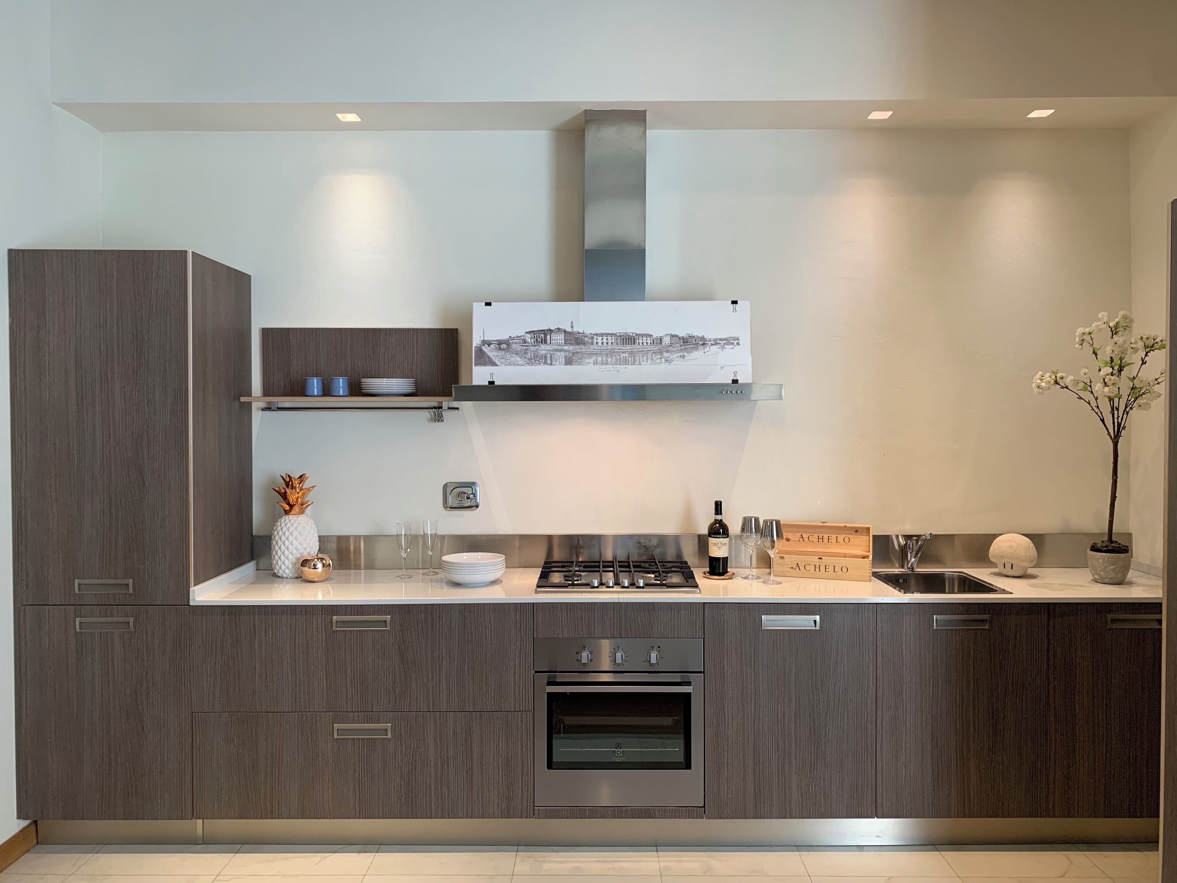 A modern kitchen with dark wood cabinetry, a stainless steel range hood, and a built-in oven.