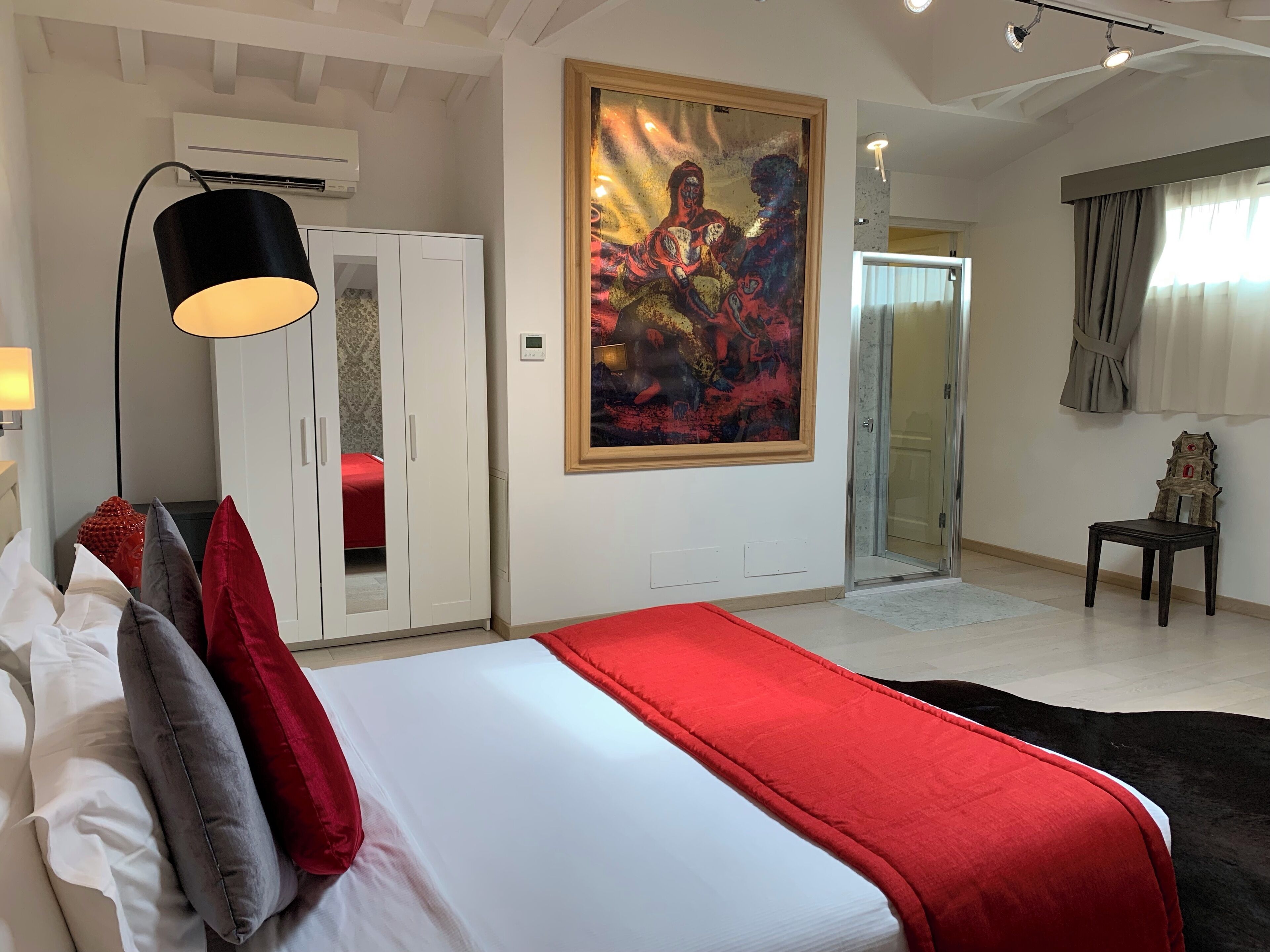 A bedroom with a bed, a wardrobe, a painting, a chair, and a door.