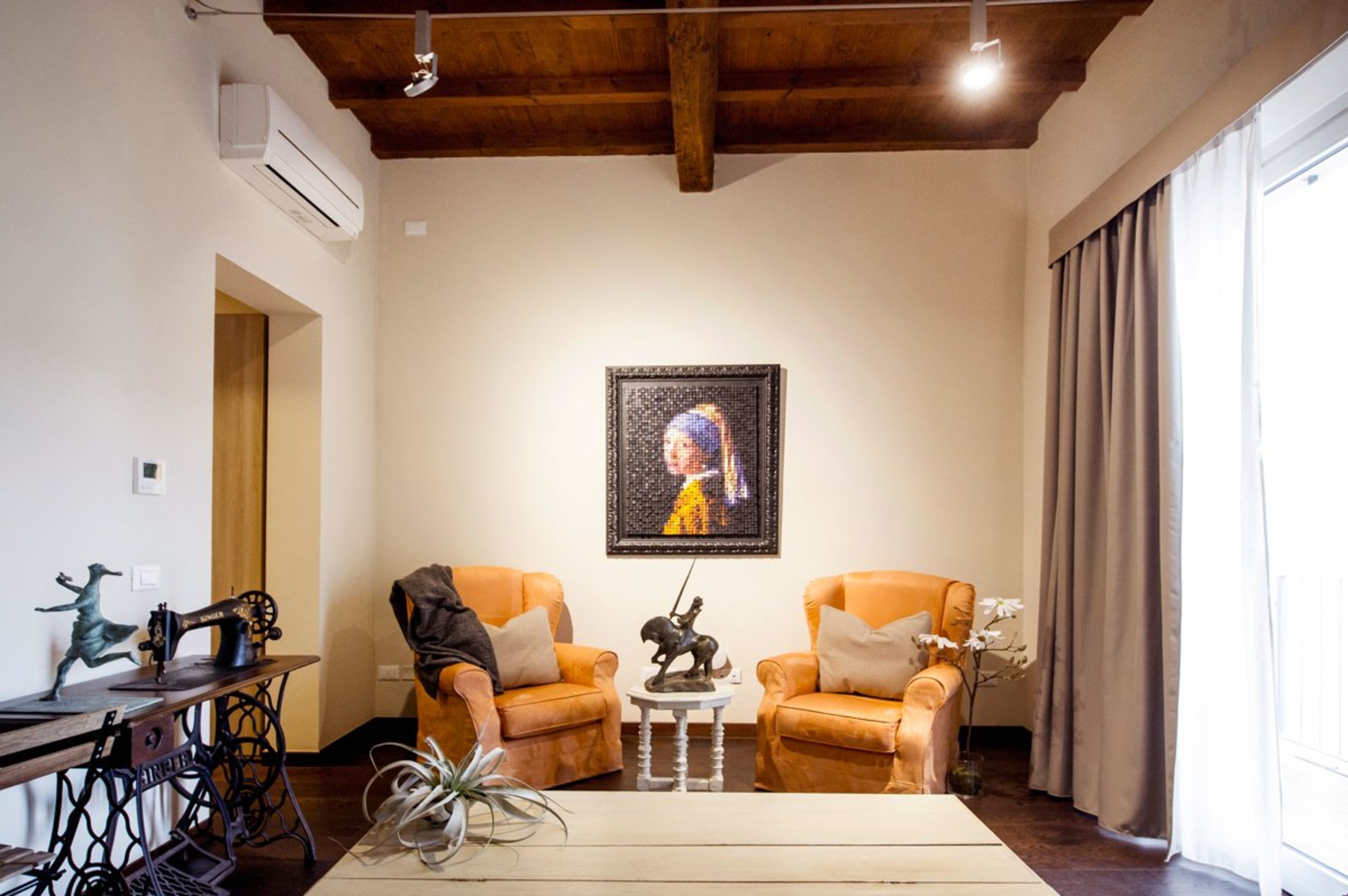 Een gezellige woonkamer met twee leren fauteuils, een klein tafeltje met een beeldje en een ingelijst kunstwerk aan de muur.
