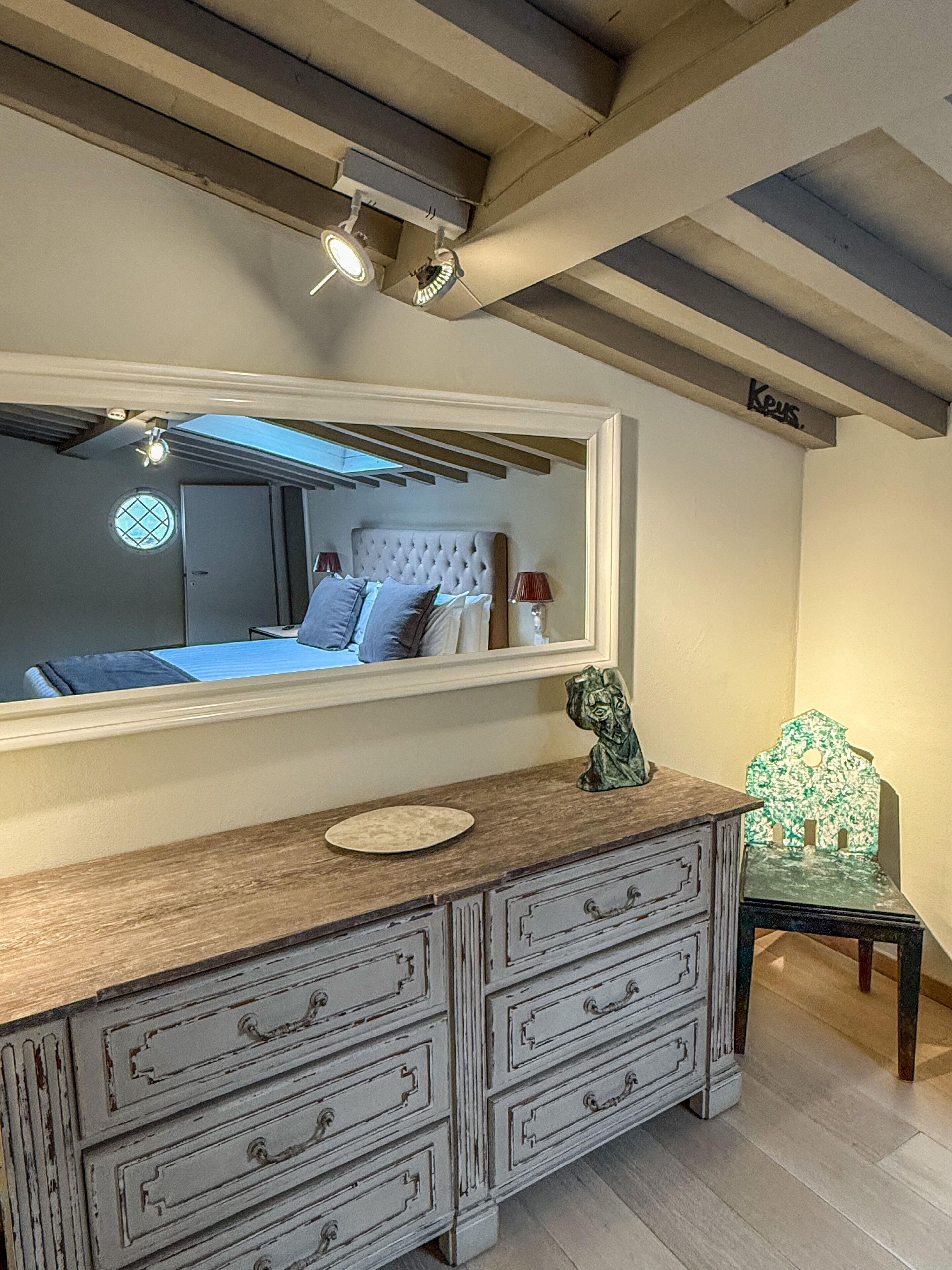 A bedroom with a large bed, a dresser, a mirror, and a window.