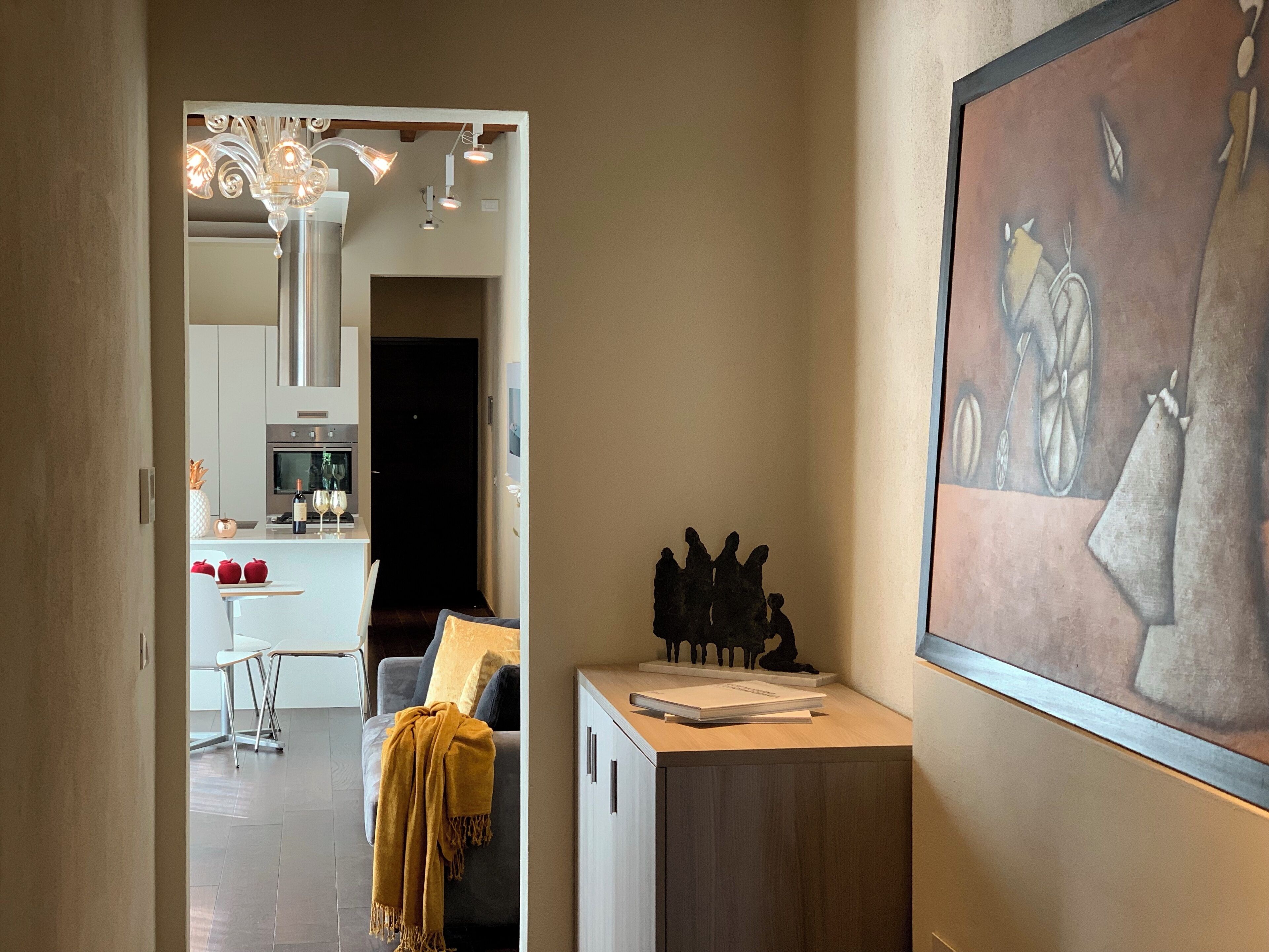 A hallway with a dining area, kitchen, and a painting on the wall.