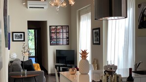 Una cocina moderna con una isla central, un área de comedor con sofá y una sala de estar con televisor.