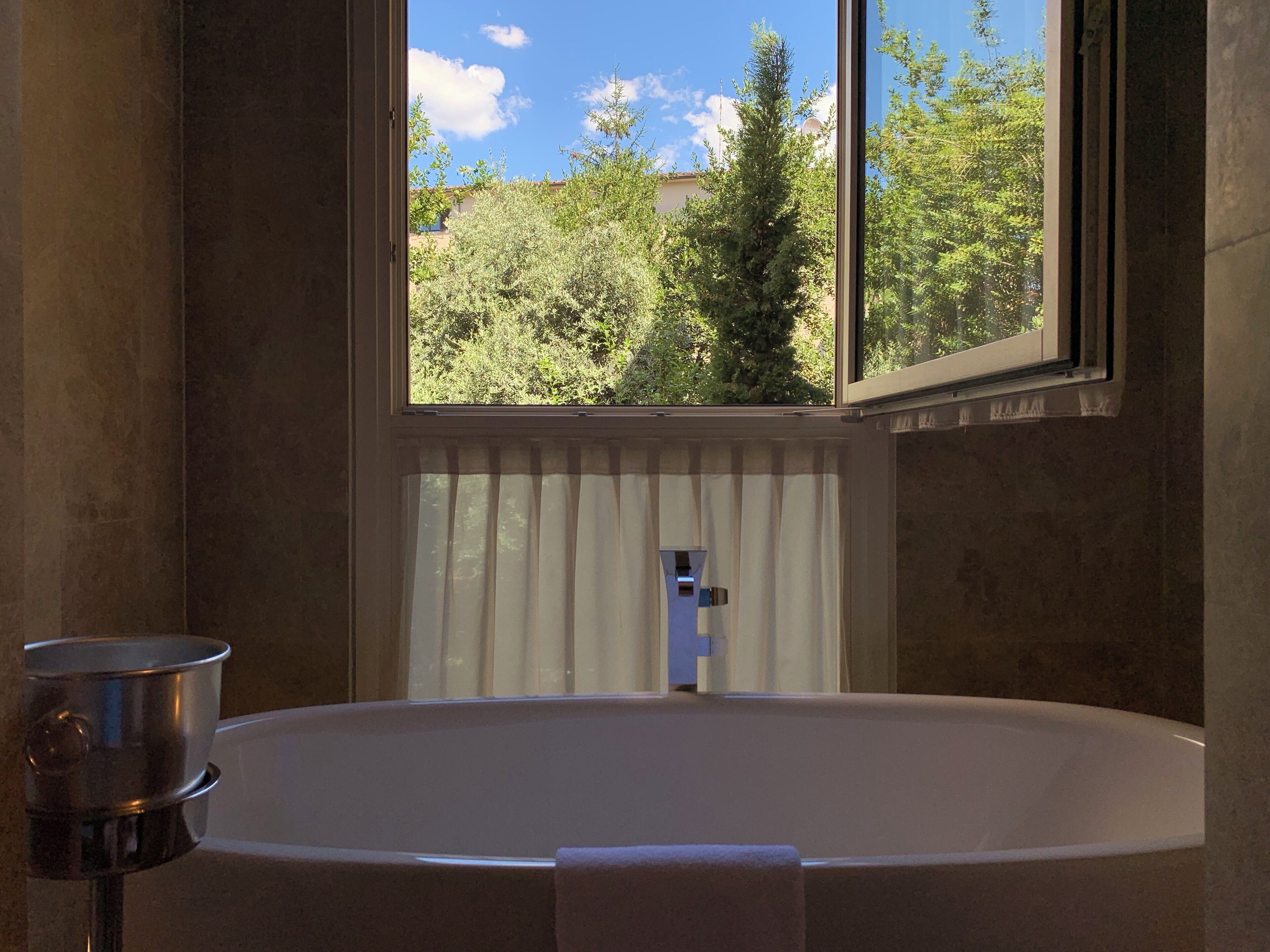 A bathroom with a freestanding bathtub, a window with a view of trees, and a towel rack.