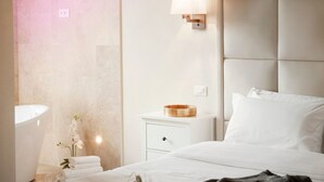 Habitación de hotel con cama, mesita de noche, lámpara y un espejo en la pared.