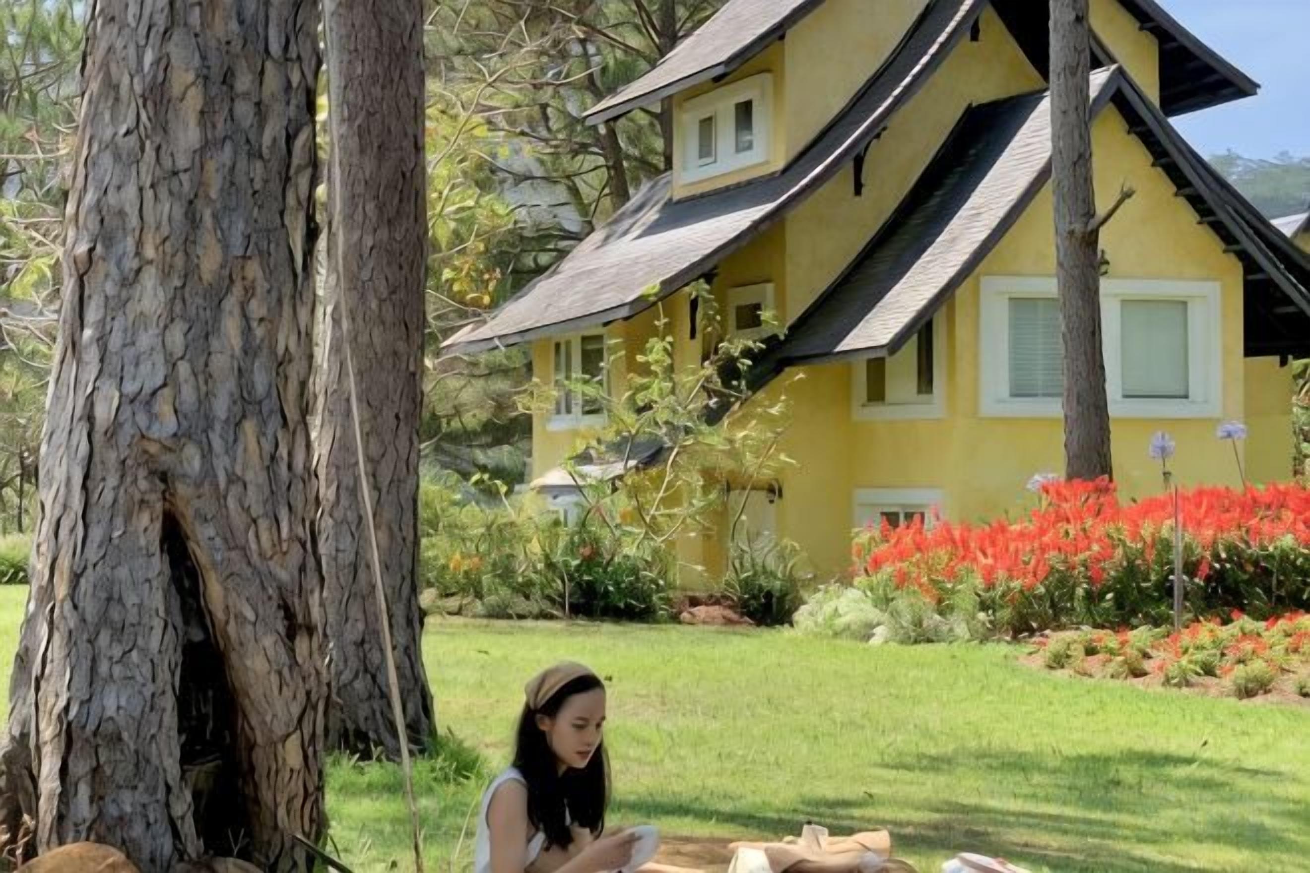 A yellow building with a sloped roof and a large tree in the foreground.
