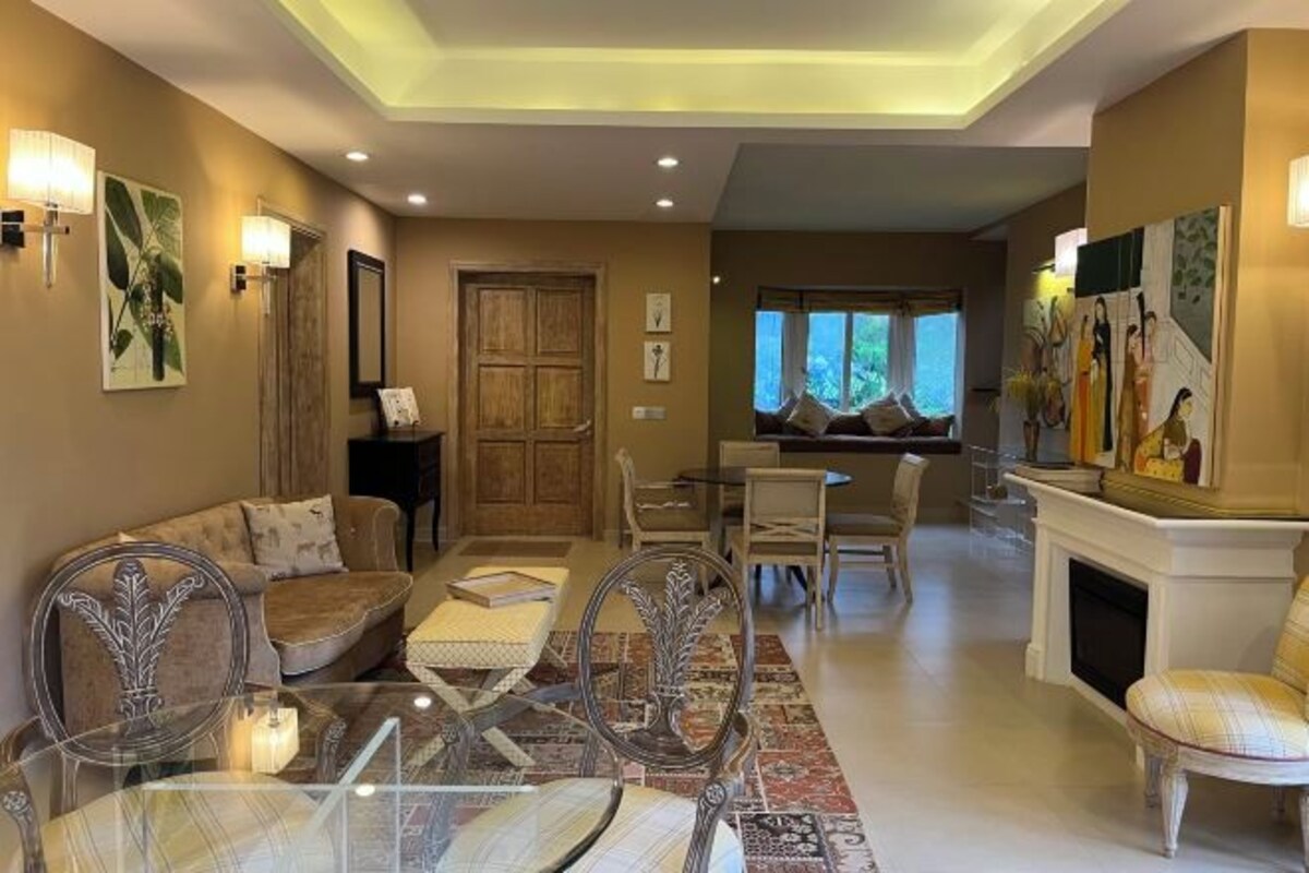 A spacious living area with a sofa, chairs, a dining table, and a fireplace.