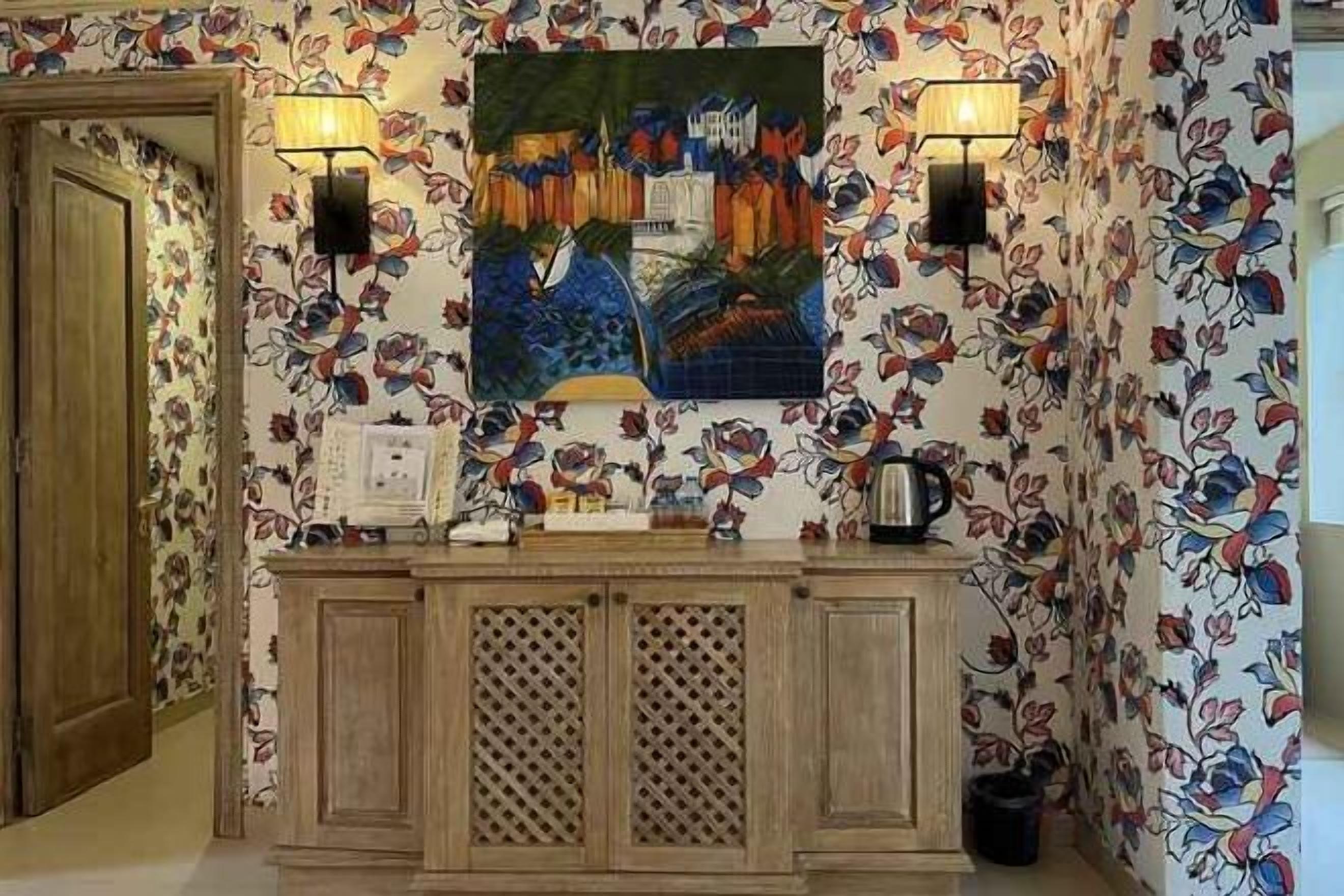 Un espace d’accueil avec un comptoir en bois, deux lampes fixées au mur et un tableau coloré au-dessus.