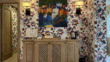 Un espace d’accueil avec un comptoir en bois, deux lampes fixées au mur et un tableau coloré au-dessus.