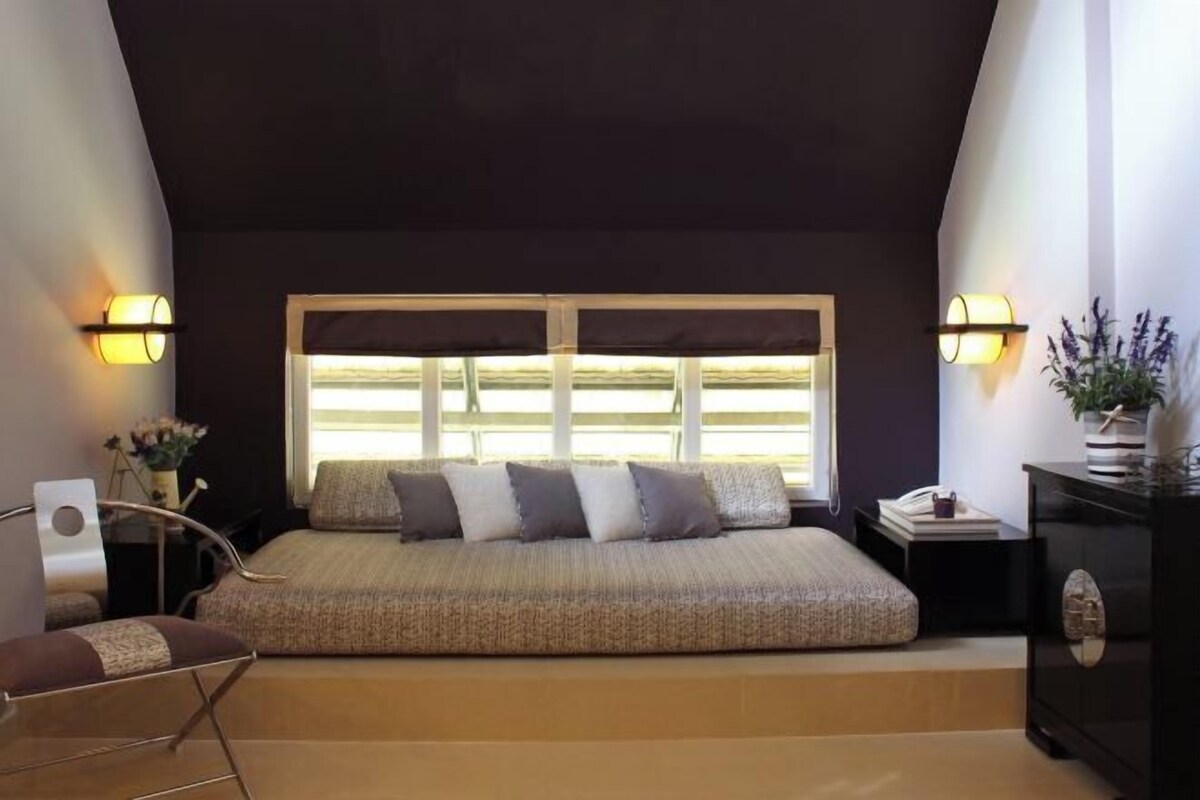 A bedroom with a bed, bedside tables, a chair, and a window with curtains.