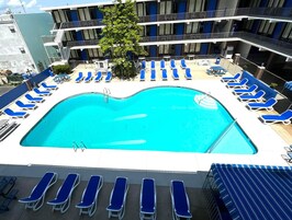 Una piscina al aire libre, sillones reclinables de piscina