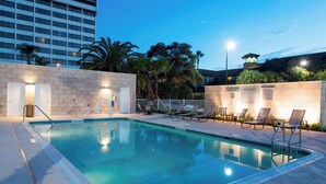 A swimming pool with lounge chairs and a lifeguard tower, surrounded by palm trees and a building in the background. - Fairfield Inn & Suites Tampa Westshore / Airport (Tampa)