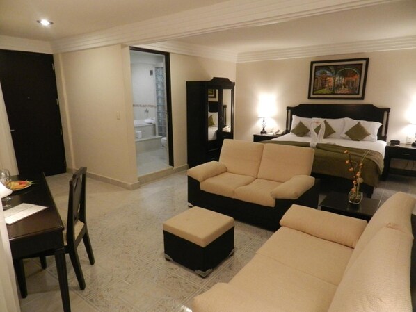 A hotel room with a bed, a sofa, a dining table with chairs, and a bathroom visible through an open door. - Hotel Victoria Merida (Mérida)