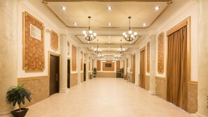 A long, well-lit hallway with chandeliers, columns, and potted plants. - Hotel Victoria Merida (Mérida)
