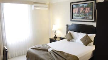 Una habitación de hotel con una cama, una mesita de noche, una lámpara y un cuadro en la pared.