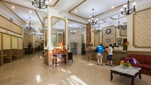A spacious lobby with a reception desk, a clock, and a red sofa. - Hotel Victoria Merida (Mérida)