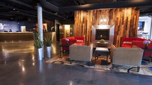 A modern lobby with a reception desk, seating area with red sofas, and a wooden accent wall. - Warehouse Hotel (Manheim)