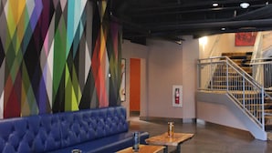 A modern interior with a blue sofa, wooden tables, and a colorful geometric wall. - Warehouse Hotel (Manheim)