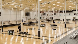 A spacious indoor gymnasium with a polished wooden floor, multiple basketball courts, and seating areas. - Warehouse Hotel (Manheim)