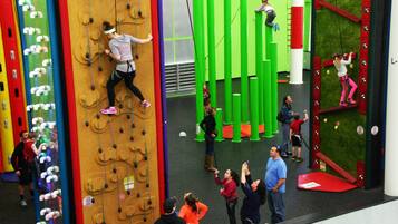 A climbing wall with various routes and a group of people observing.