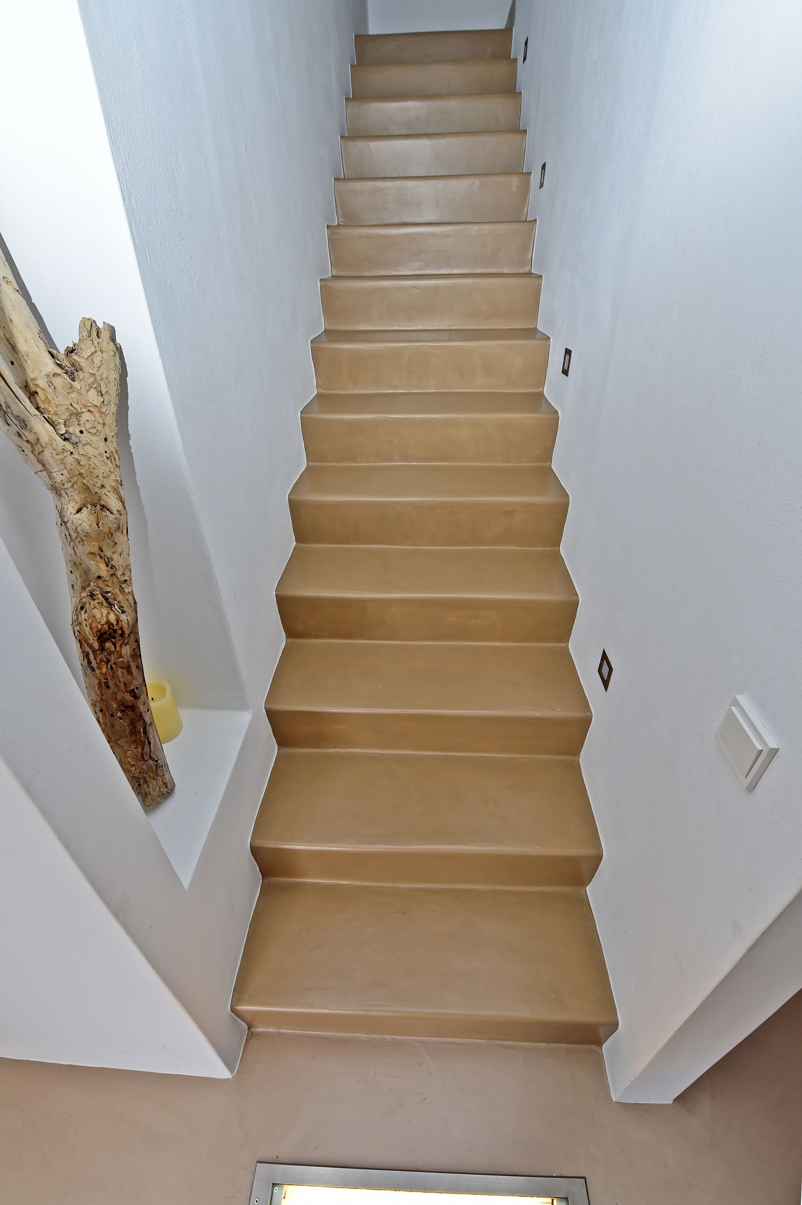 Una escalera con peldaños color beige y paredes blancas.