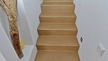 Una escalera con peldaños color beige y paredes blancas.