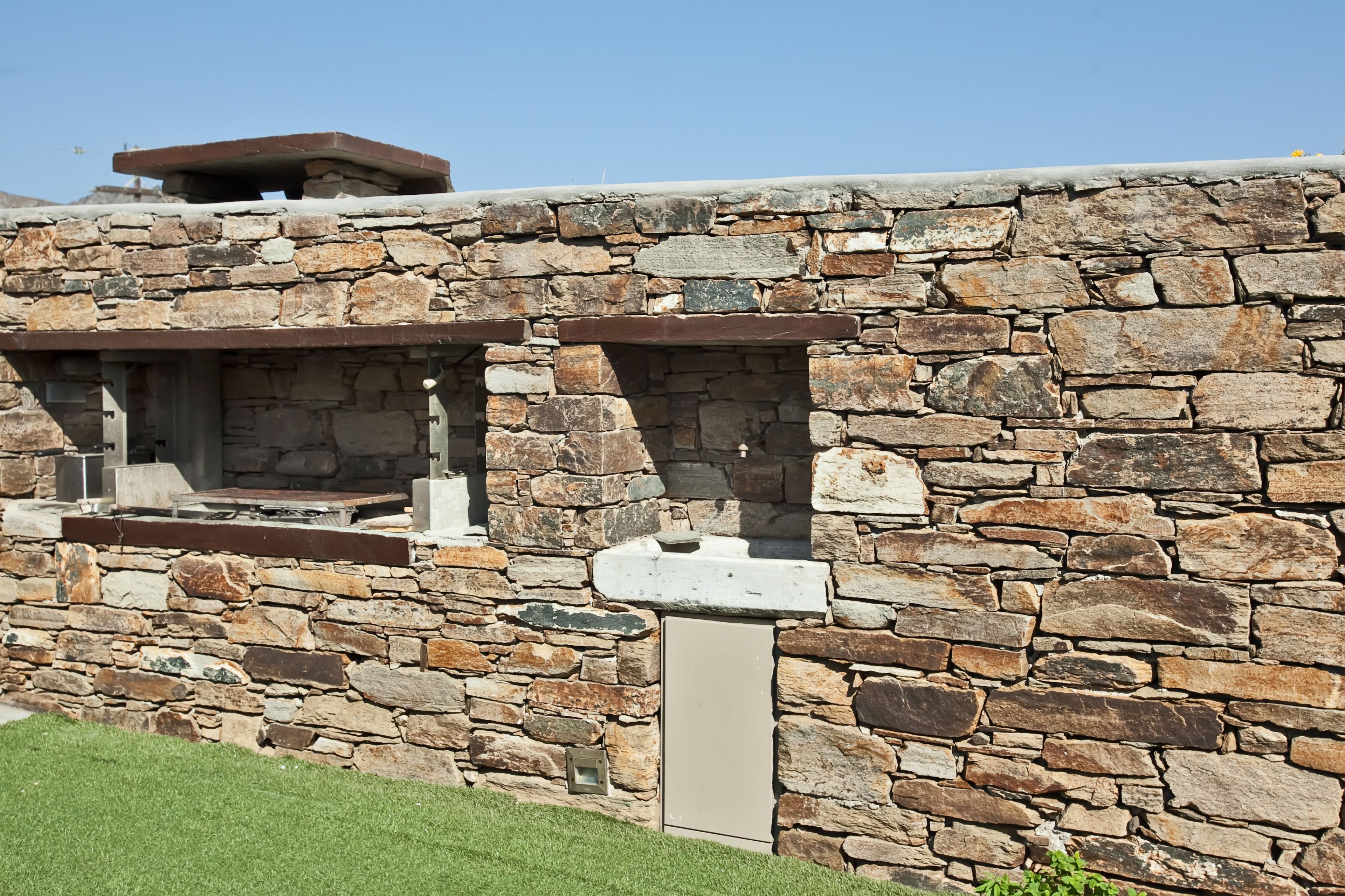 Pared de piedra con chimenea integrada y un ventanal pequeño.