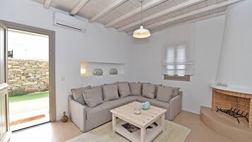 A modern living room with a stone wall, a beige sectional sofa, a wooden coffee table, and a fireplace.