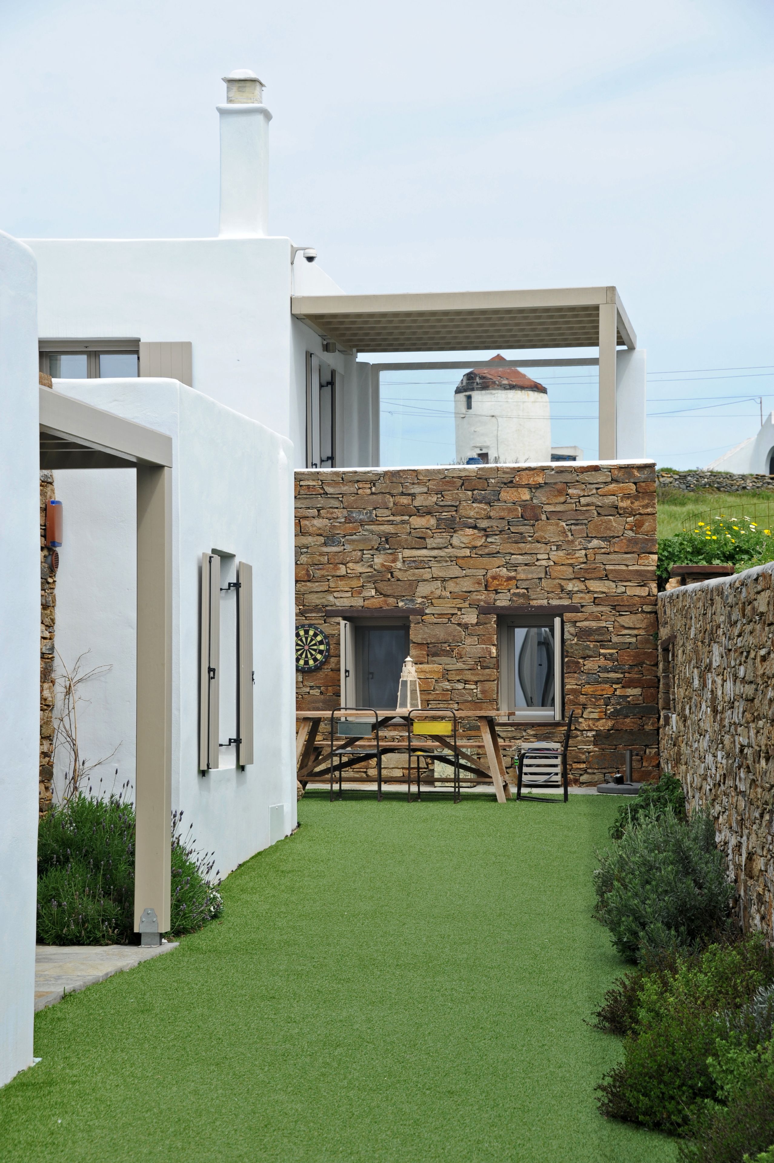 Una casa moderna con fachada de piedra, césped verde y vista al mar.