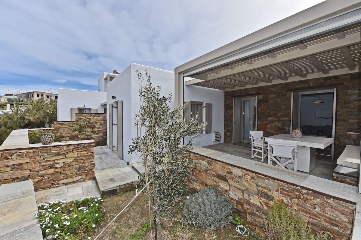 Een modern huis met een stenen gevel, een terras met tuinmeubilair en uitzicht op de omliggende wijk.