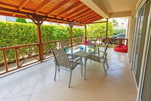 A covered outdoor area with a glass table and chairs, surrounded by a metal railing. - Paradise Town Villa Alison (Serik)