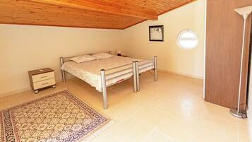 Quarto com cama, mesa de cabeceira, luminária e teto de madeira.