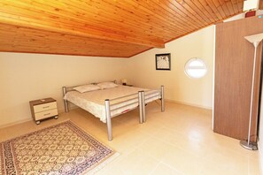 A bedroom with a bed, a nightstand, a bedside table, a lamp, and a wooden ceiling. - Paradise Town Villa Alison (Serik)