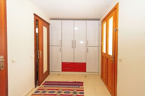 A hallway with a wardrobe, a patterned rug, and wooden doors. - Paradise Town Villa Alison (Serik)