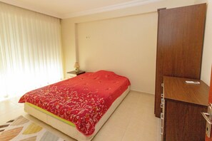 A bedroom with a bed, a wooden wardrobe, a nightstand, and a lamp. - Paradise Town Villa Alison (Serik)