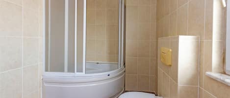 A bathroom with a shower enclosure, toilet, and a towel rack.