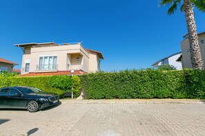 A modern two-story house with a balcony, a paved driveway, and a well-maintained hedge. - Paradise Town Villa Alison (Serik)