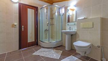 A bathroom with a glass shower enclosure, a sink, and a toilet.