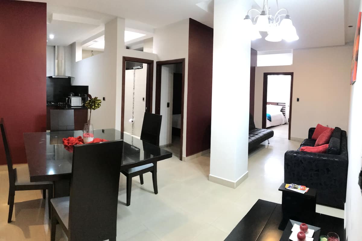 A modern living space with a dining area, a kitchen, and a seating area with a sofa and a coffee table.