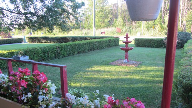 A well-maintained garden with a central fountain, neatly trimmed hedges, and a variety of flowers. - The New Elgin Motel (Saint Thomas)