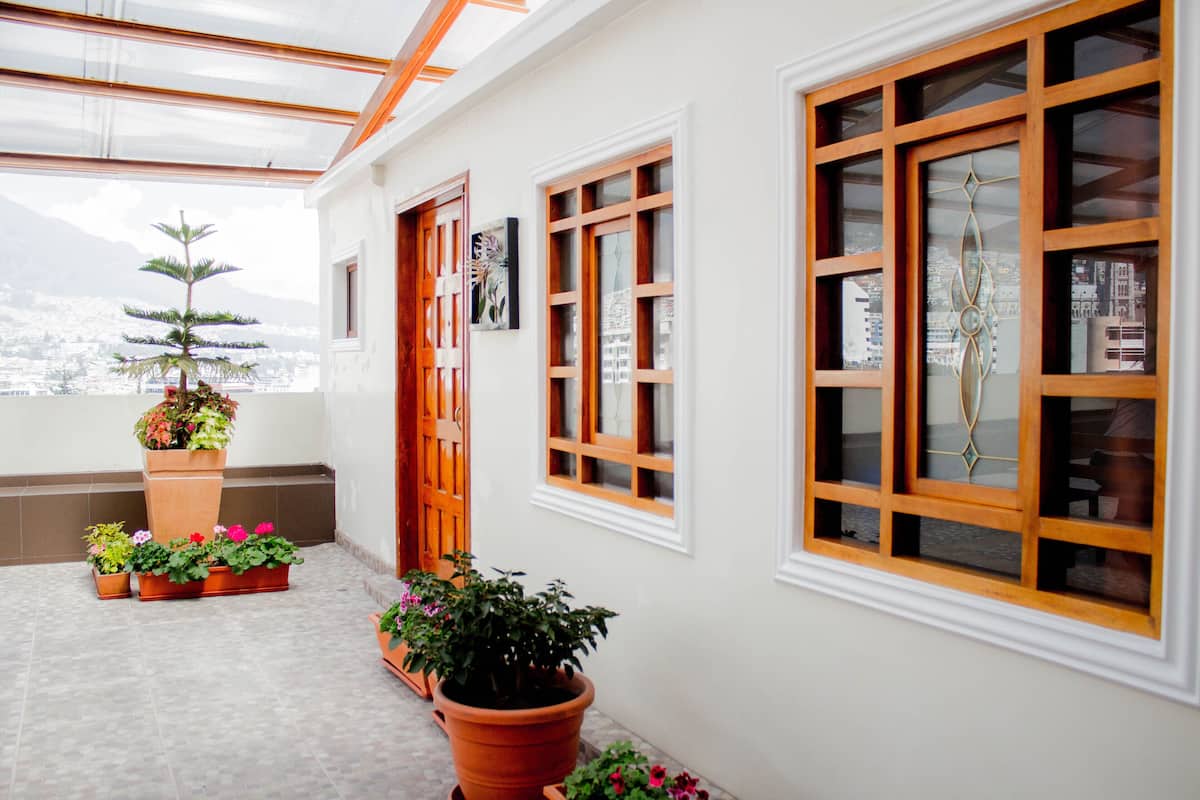 A sunlit interior with a large window, wooden doors, and potted plants.