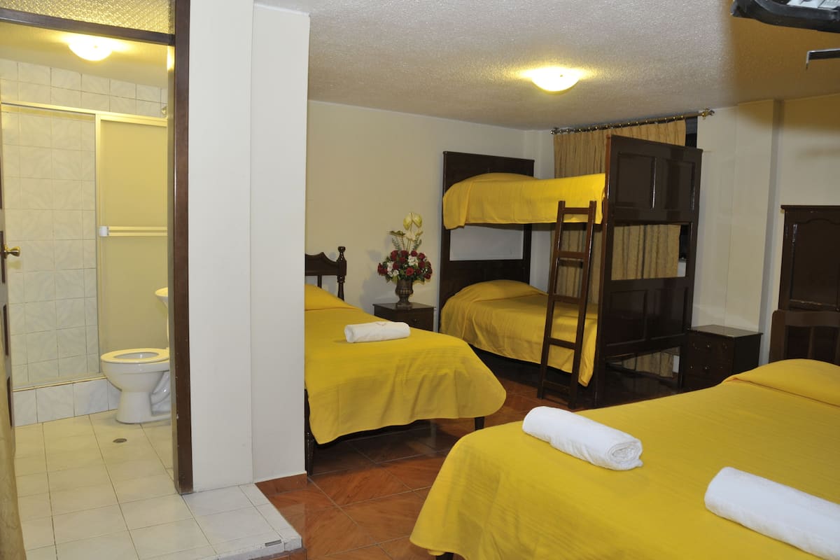 A room with bunk beds, a toilet, and a shower area.